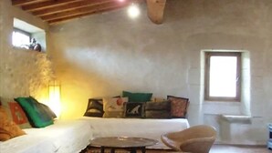 Una sala de estar rústica con techo de madera, un sofá con cojines, una mesa de centro y una ventana.