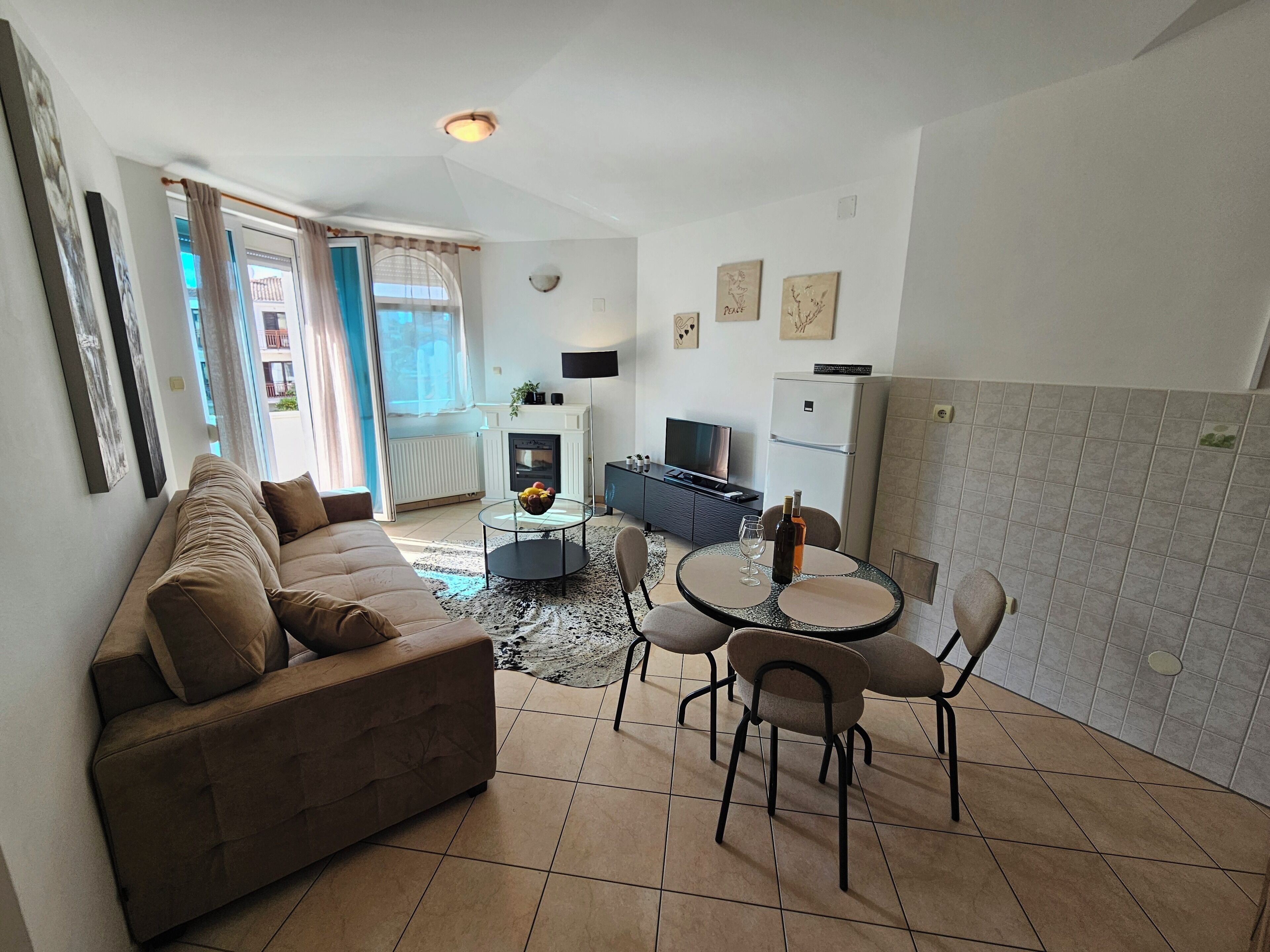 A living room with a sofa, a dining table with chairs, a TV, and a fireplace.