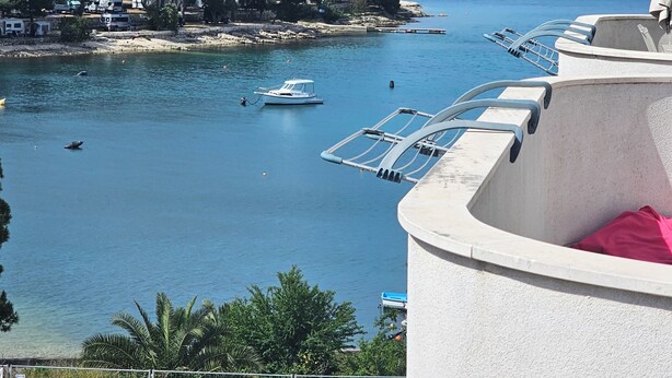 Une vue sur la côte, avec un quai pour bateaux, une eau d’un bleu limpide et un paysage vallonné en arrière-plan.
