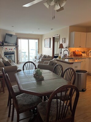A spacious living area with a dining table, sofas, and a kitchen in the background.