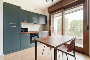 A modern kitchen with dark cabinets, a wooden table, and a view of the outside. - Bright 41m2 studio apartment, ideal for 2 people, located on the third floor of a building with lift.The accommodation is located in a quiet residential area, known for its direct view of the Parco Nord Milano.Served by the Milano Bruzzano FN station (su (Milano)