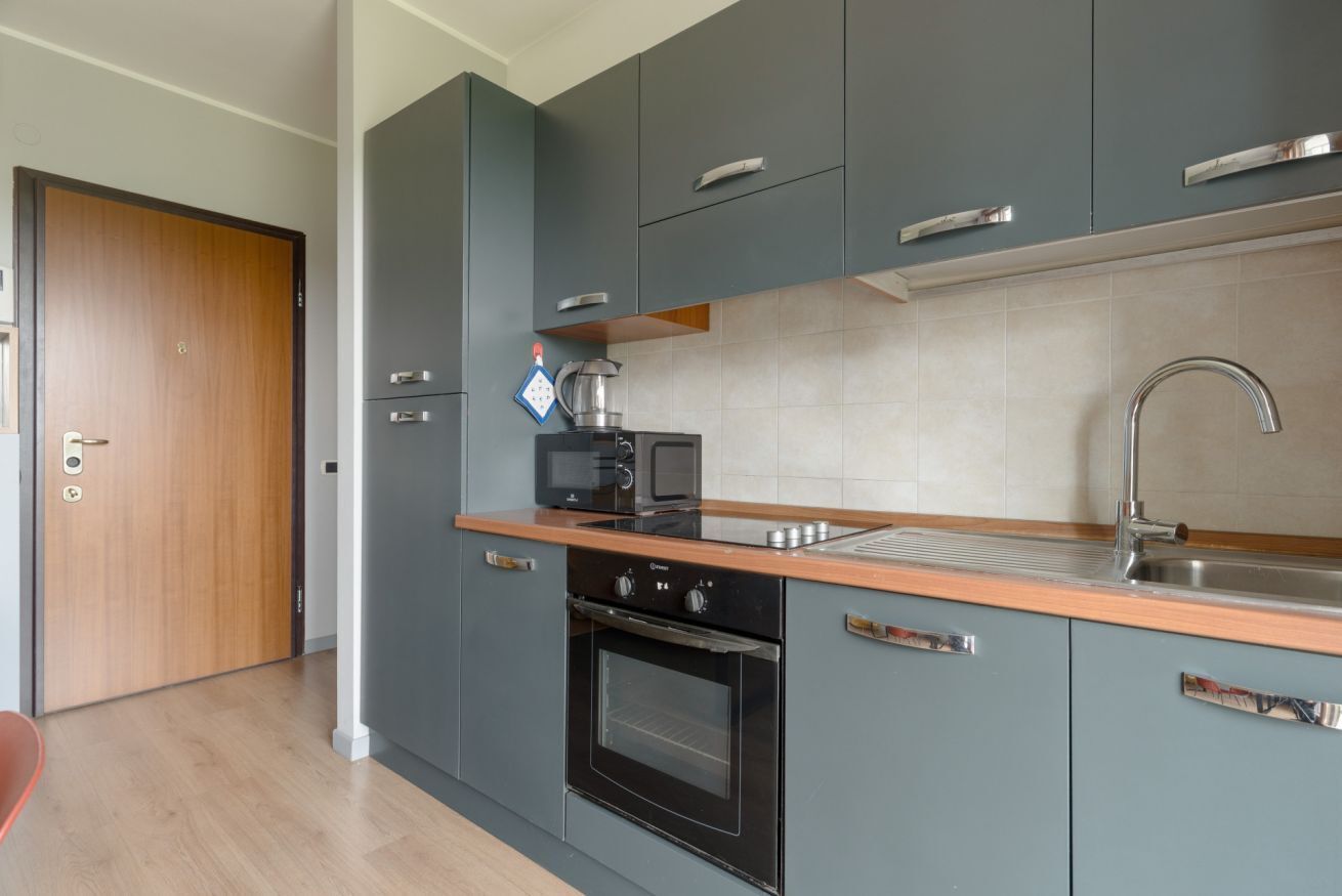 Una cucina moderna con mobili grigi, un lavello in acciaio inossidabile, un forno a microonde e un forno.