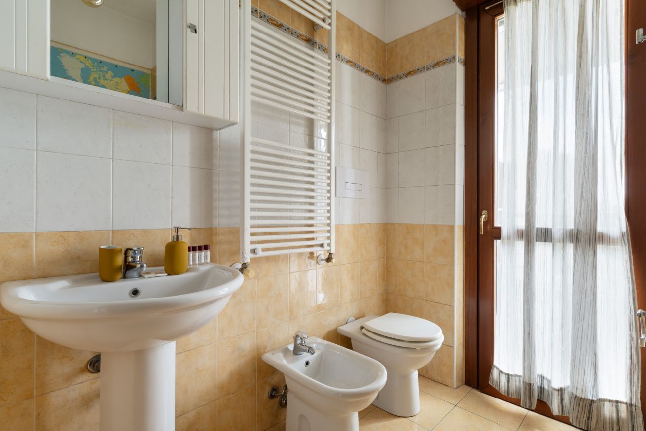 A bathroom with a sink, bidet, toilet, and a towel rack.