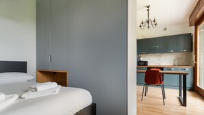 Ein modernes Hotelzimmer mit Bett, Schreibtisch und einer Küchenzeile.