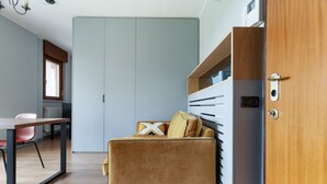 Ein kleines Zimmer mit einer Couch, einem Tisch und einer Holztür.