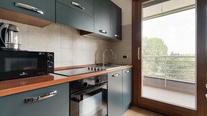 Eine moderne Küche mit Mikrowelle, Backofen und Spüle, sowie ein Balkon mit Aussicht.