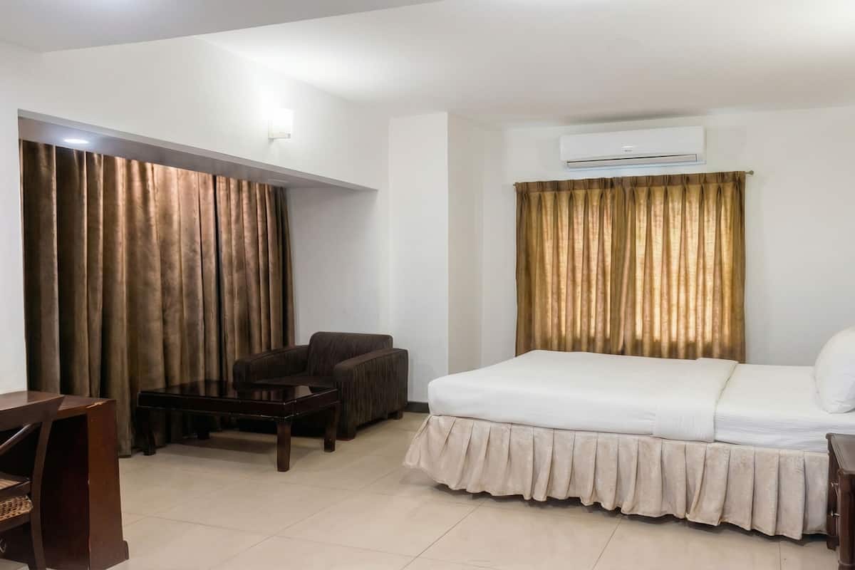 Habitación de hotel con cama, escritorio, silla y equipo de aire acondicionado.