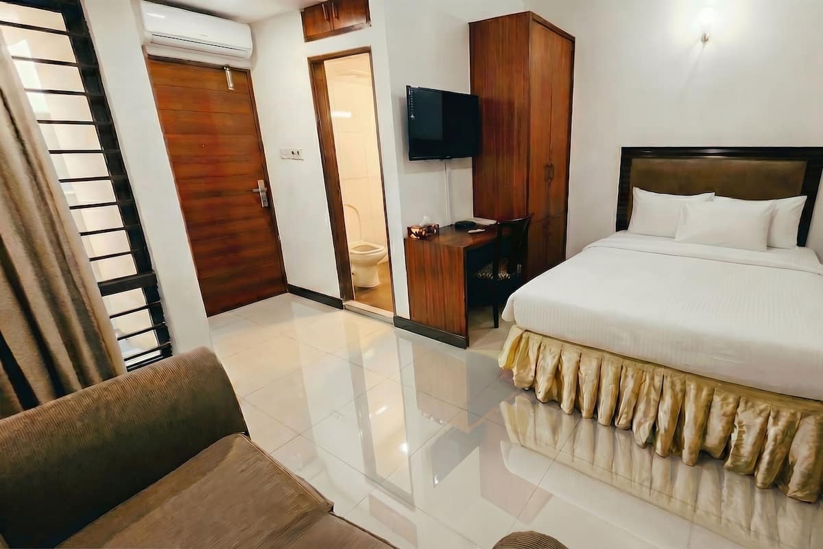 Una habitación de hotel con cama, escritorio, televisor y armario.