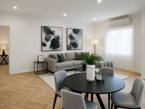 Ein modernes Wohnzimmer mit einer Couch, einem runden Tisch und zwei abstrakten Bildern an der Wand.