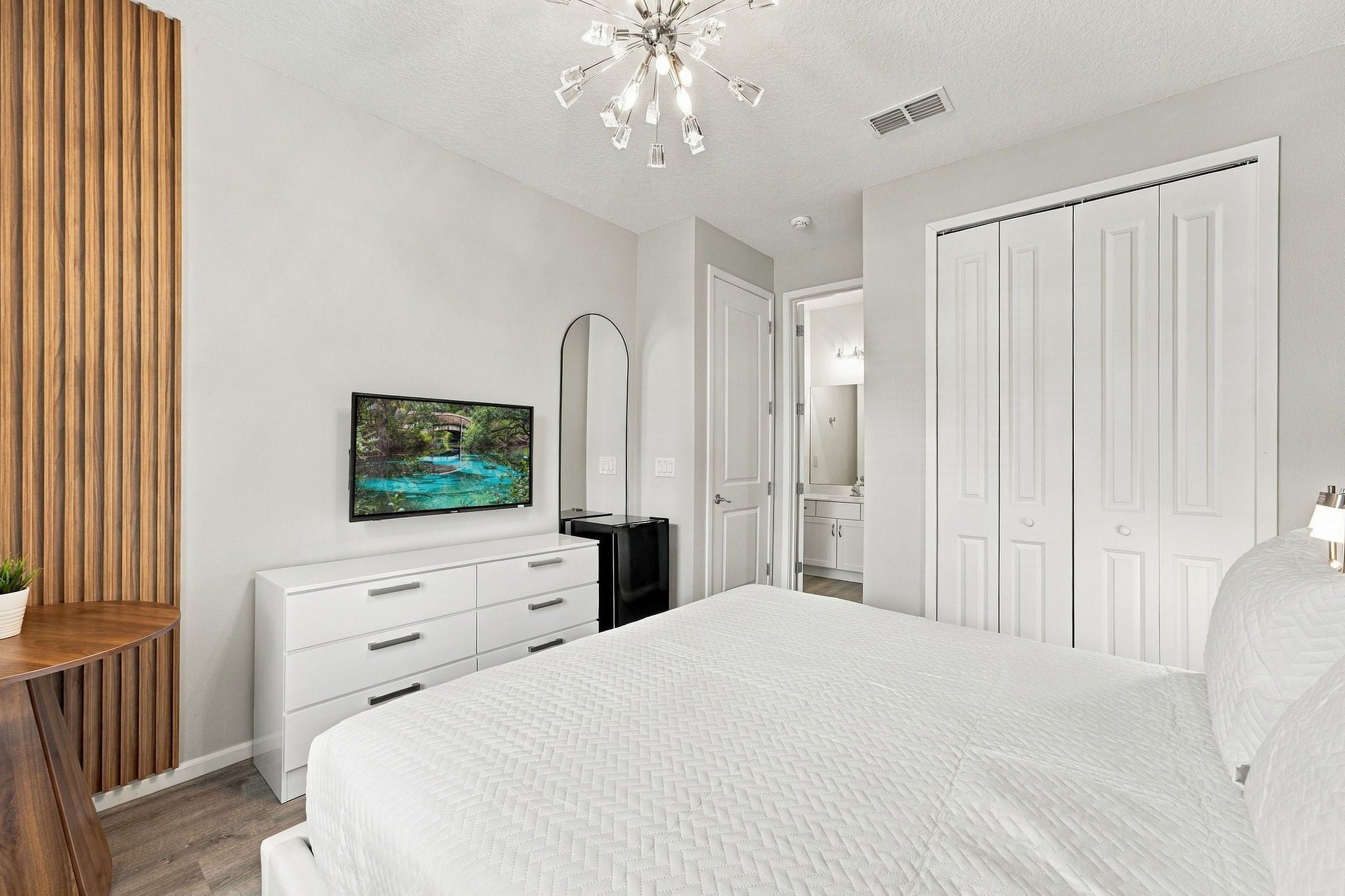 A bedroom with a bed, a dresser, a television, and a wardrobe.
