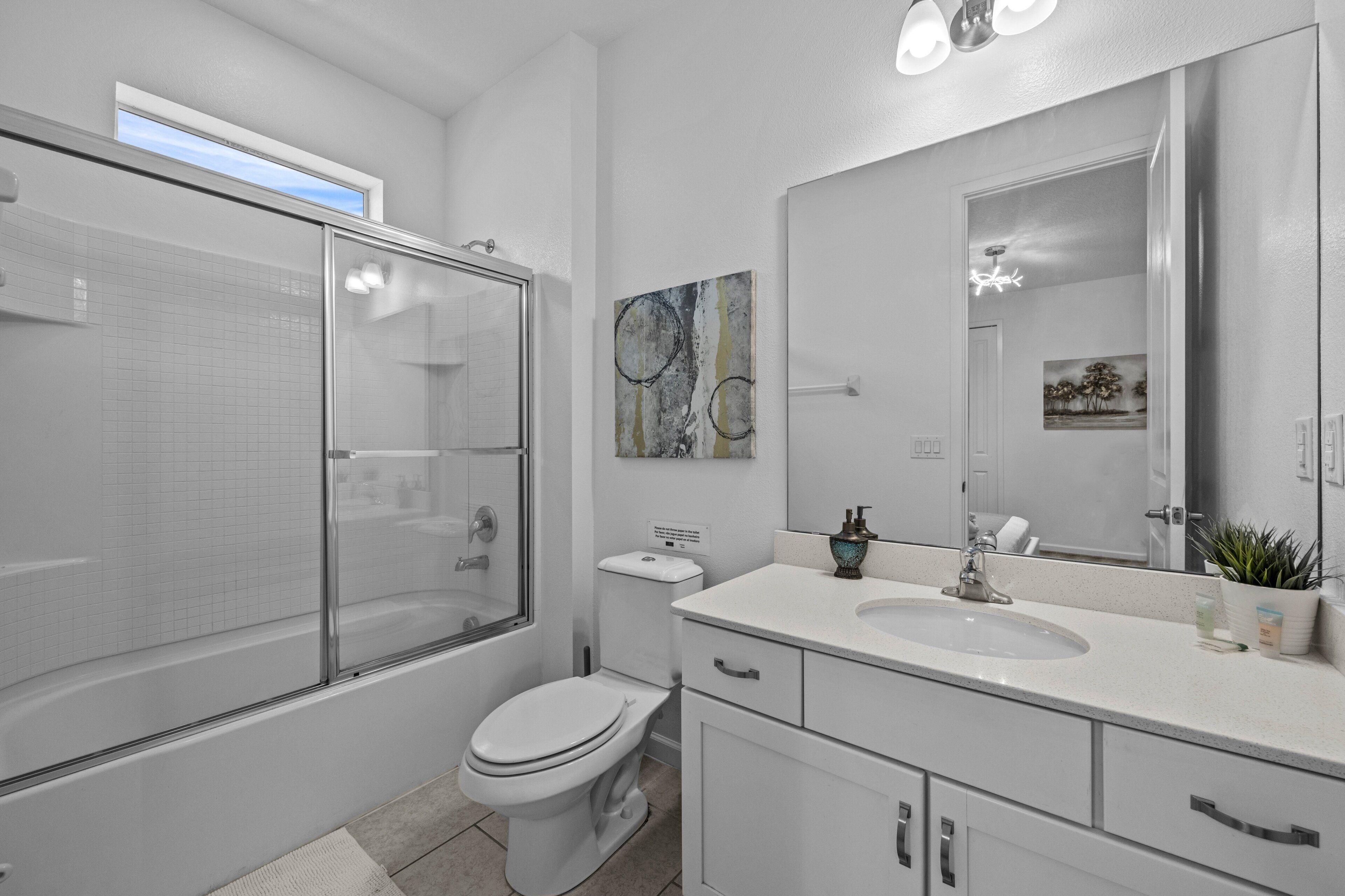 A modern bathroom with a glass shower enclosure, a toilet, a sink, and a large mirror.