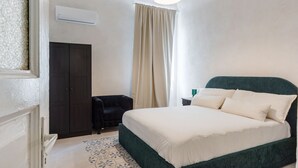 Um quarto com cama, guarda-roupa, cadeira e janela com cortinas.