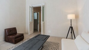 Um quarto com um sofá de couro marrom, um sofá branco, um abajur e um tapete estampado.