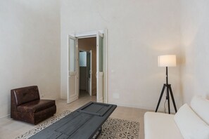 A room with a brown leather sofa, a white sofa, a floor lamp, and a patterned rug. - Ai Benedettini Apartment by Wonderful Italy (Catania)