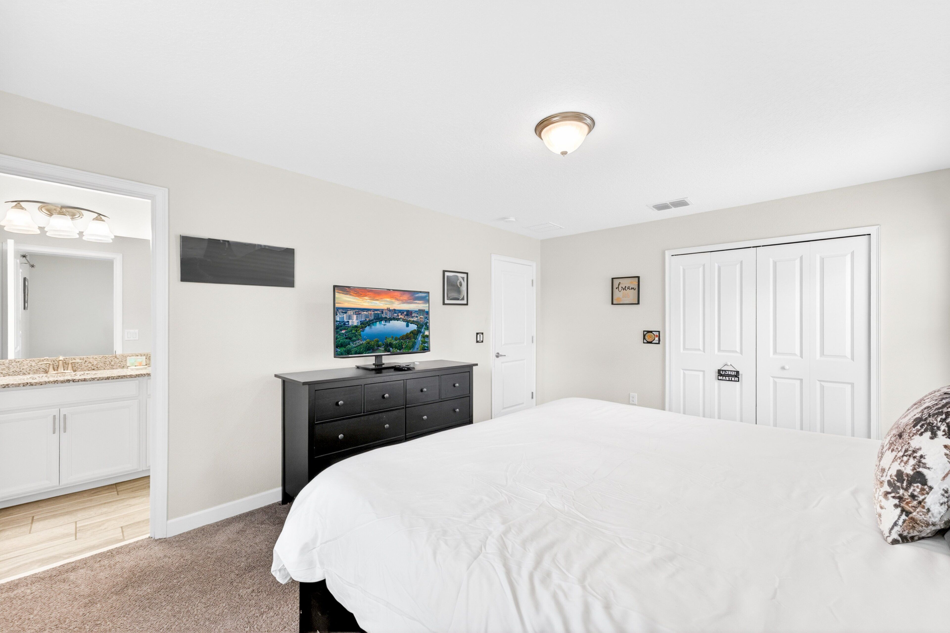 A bedroom with a bed, dresser, TV, and a door with a sign.