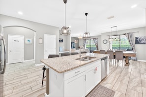 A modern kitchen with a granite countertop, white cabinetry, and pendant lighting. - Sol117-5484-6-pg - Solterra's Dream Home (Davenport)