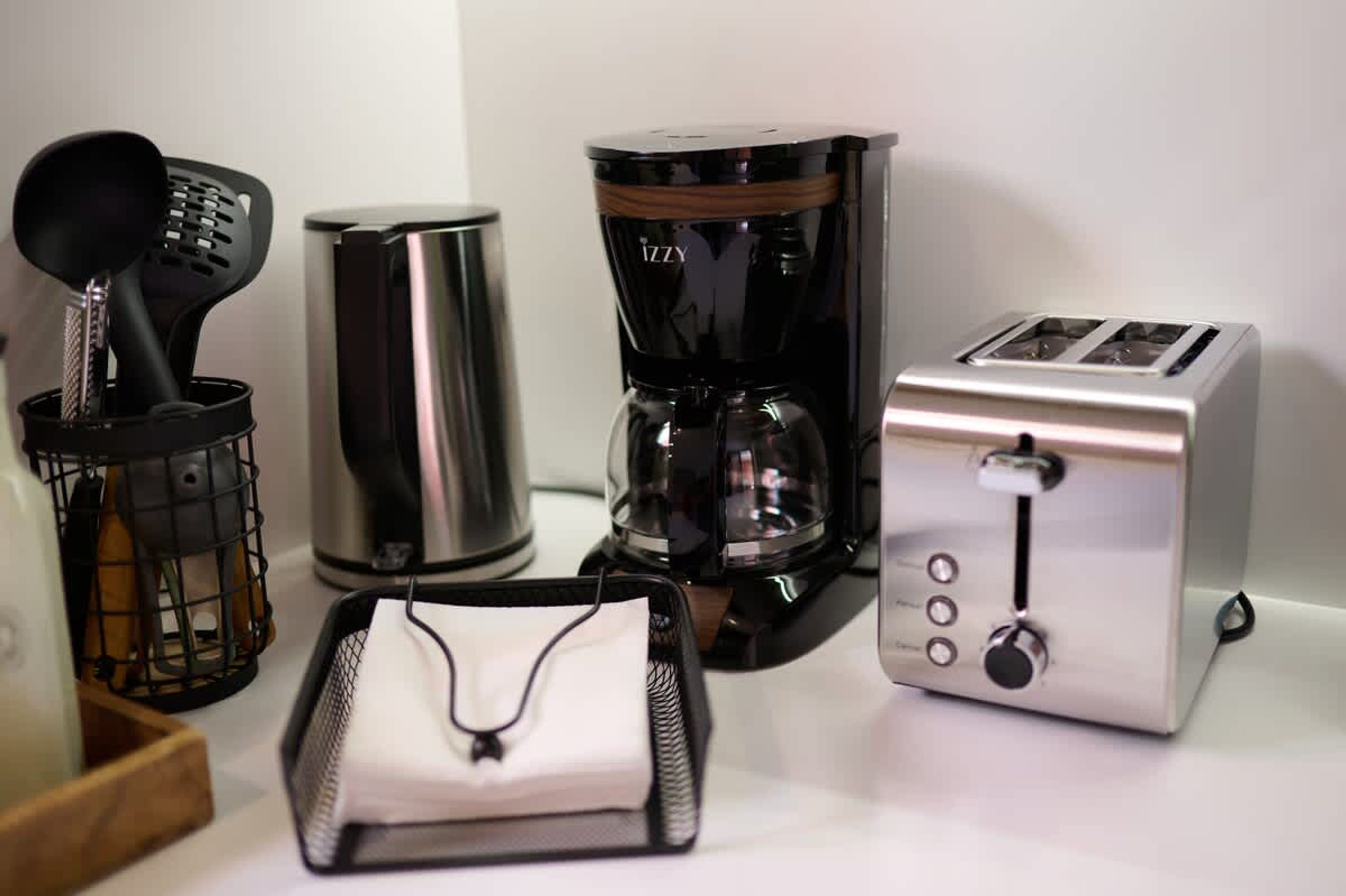 Una cocina con cafetera, tostadora y una espátula negra en una cesta.