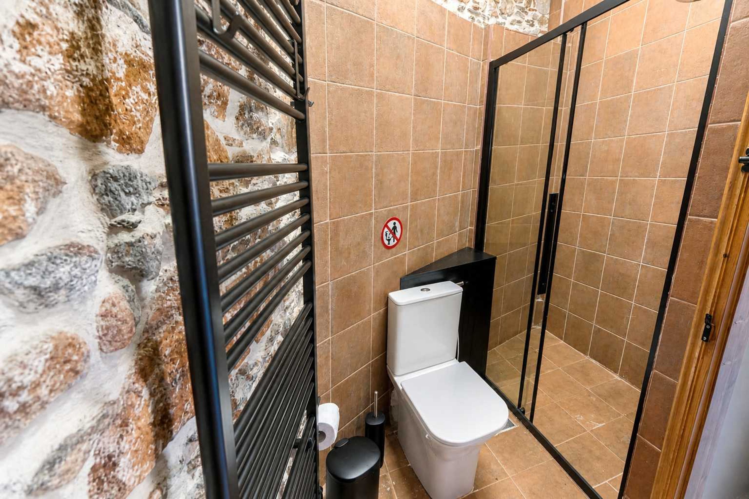 A bathroom with a toilet, a shower, and a no-entry sign.
