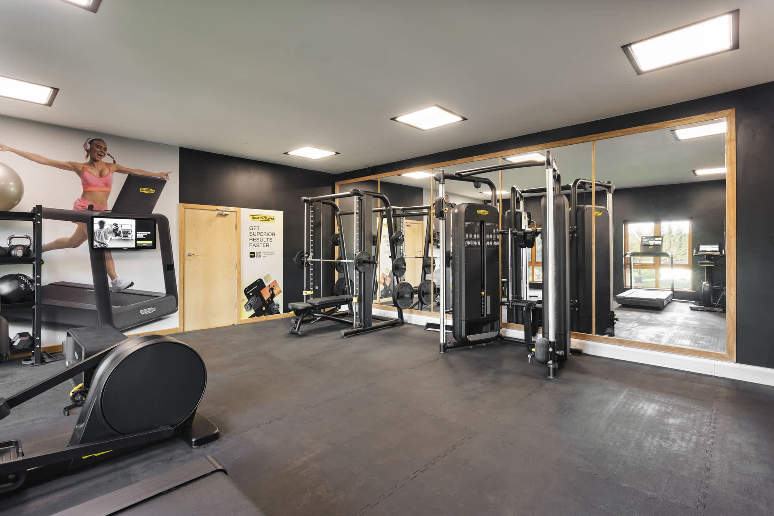 Une salle de sport équipée de tapis de course, d’appareils de musculation et d’un mur recouvert de miroirs.