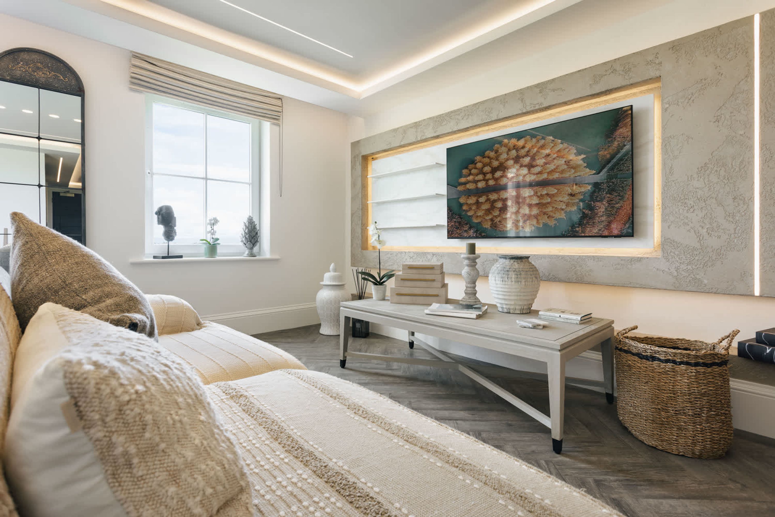 Una sala de estar moderna con un cuadro grande, un sofá, una mesa de centro y una ventana con adornos decorativos.
