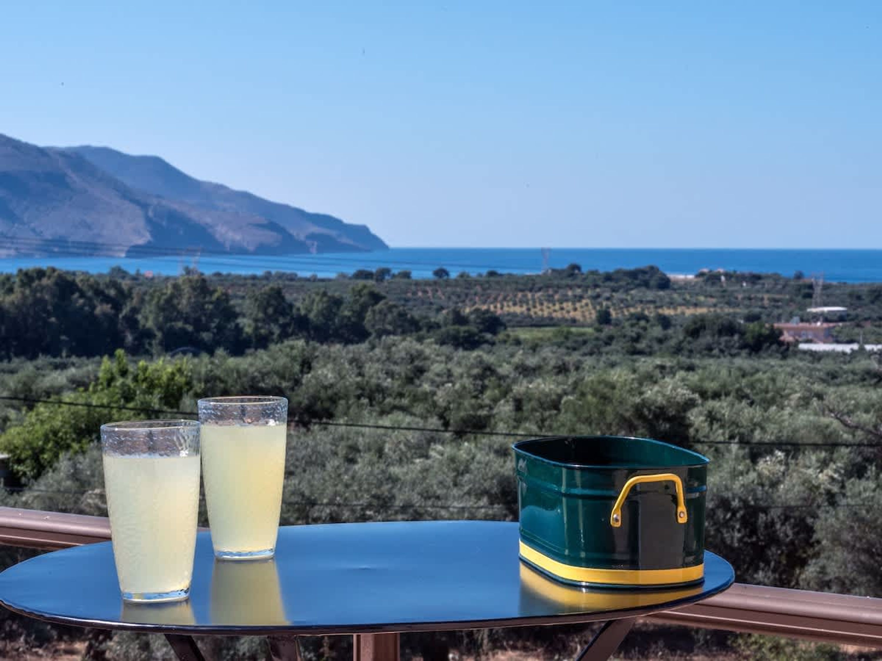 Un tavolo con due bicchieri e un contenitore verde.