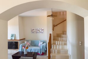 A living room with a sofa, coffee table, fireplace, and staircase. - The Lake House - Private Pool Views Near Kournas (Apokoronas)