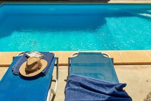 A poolside area with a lounge chair and a towel, a hat, and a book on a towel. - The Lake House - Private Pool Views Near Kournas (Apokoronas)