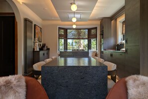 Cocina moderna con una isla de granito, iluminación colgante y vistas al exterior.