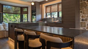 A modern kitchen with a large island, bar stools, and a stone accent wall. - Wyke View Ridgestone (Windermere)