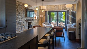 A modern kitchen with a stone wall, bar stools, and a large window. - Wyke View Ridgestone (Windermere)