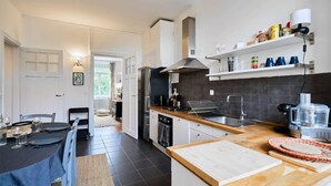A modern kitchen with a central island, built-in appliances, and a dining area with a table set for two. - Bel Appartement 2 Chambres Avec Espace Travail (Lille)