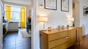 A modern kitchen with a dining area, wooden cabinets, and a view through the window. - Bel Appartement 2 Chambres Avec Espace Travail (Lille)