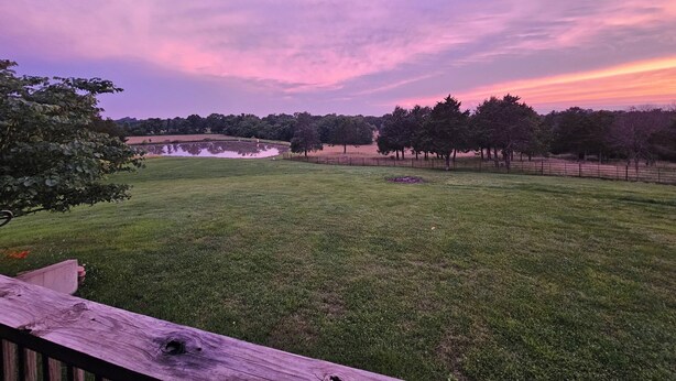 A grassy field with a pond and trees, viewed from a wooden deck. - Private Country Suite Near Truman Lake & Fishing (Clinton)