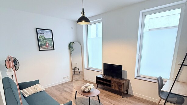 Een moderne woonkamer met een bank, een salontafel, een tv-meubel en een groot raam.