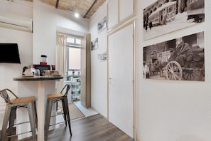 A hallway with a coffee station, two stools, a TV, and a door leading to a balcony. - Apartment 'Termini Suite Roma' with Wi-Fi and Air Conditioning (Roma)