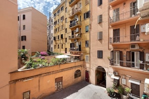 A narrow urban street with multi-story buildings, balconies with railings, and potted plants. - Apartment 'Termini Suite Roma' with Wi-Fi and Air Conditioning (Roma)