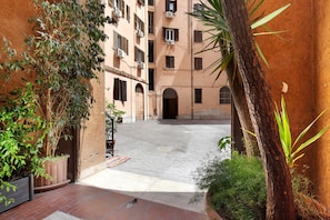 A courtyard with a paved walkway, a palm tree, and a building with multiple windows and balconies. - Apartment 'Termini Suite Roma' with Wi-Fi and Air Conditioning (Roma)