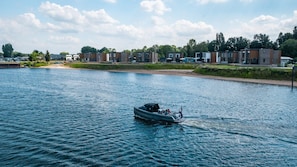Un bote en un río tranquilo con edificios modernos al fondo.