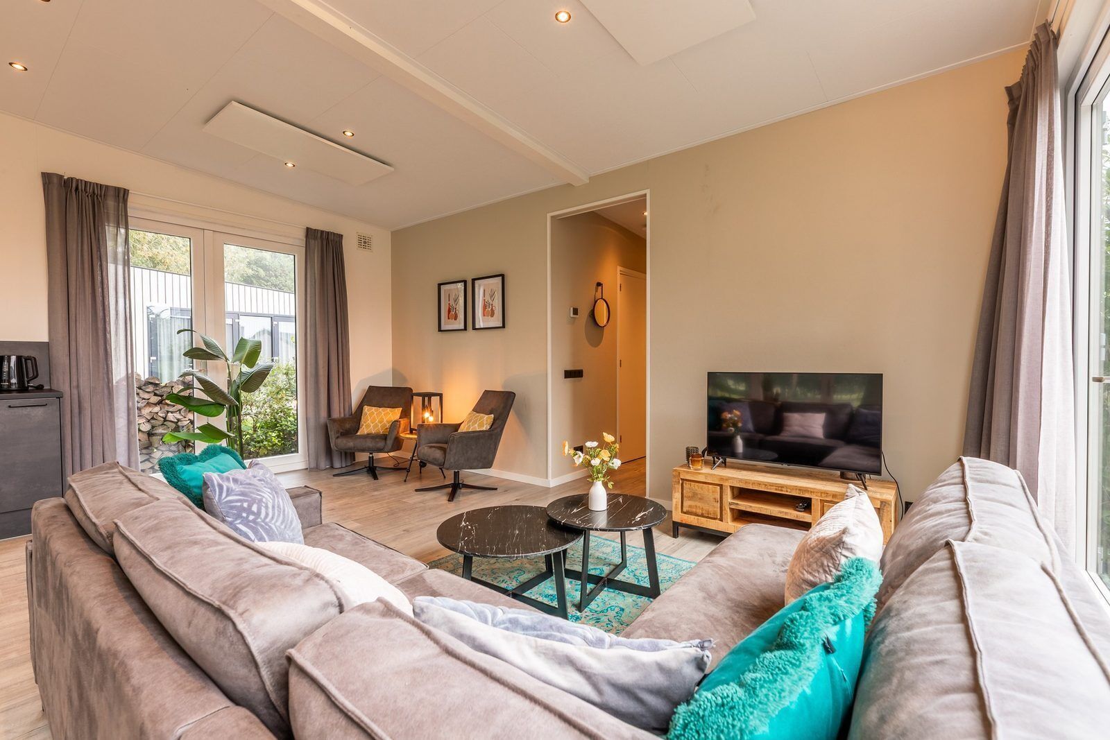 A modern living room with a sofa, chairs, a coffee table, a TV, and a dining area.