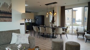 Ein modernes Wohnzimmer mit einer Couch, einem Hocker und einem Essbereich mit Stühlen und einem Tisch.