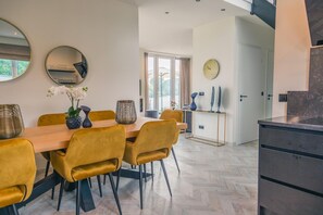 Et moderne spiseområde med et træbord, gule stole og et fiskebensmønstret gulv.