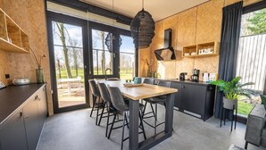 Moderni keittiö, jossa on ruokailutila, suuret ikkunat ja näkymä ulos.
