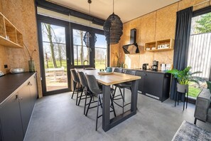 A modern kitchen with a dining area, large windows, and a view of the outdoors. - Vakantiepark Aan de Maas - Weide Lande | 4p (Kerkdriel)
