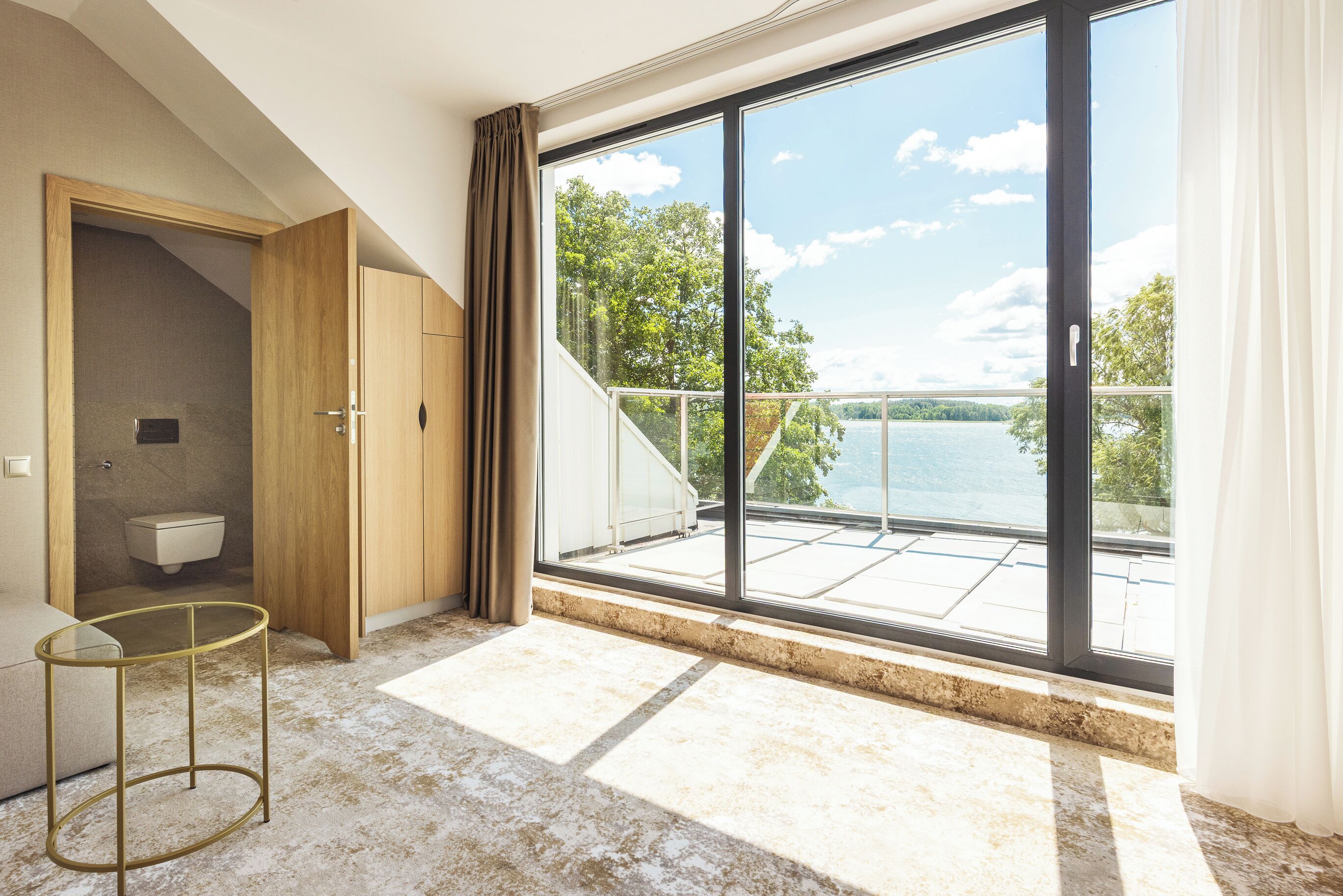 A modern bathroom with a toilet, a wooden cabinet, and a glass table.