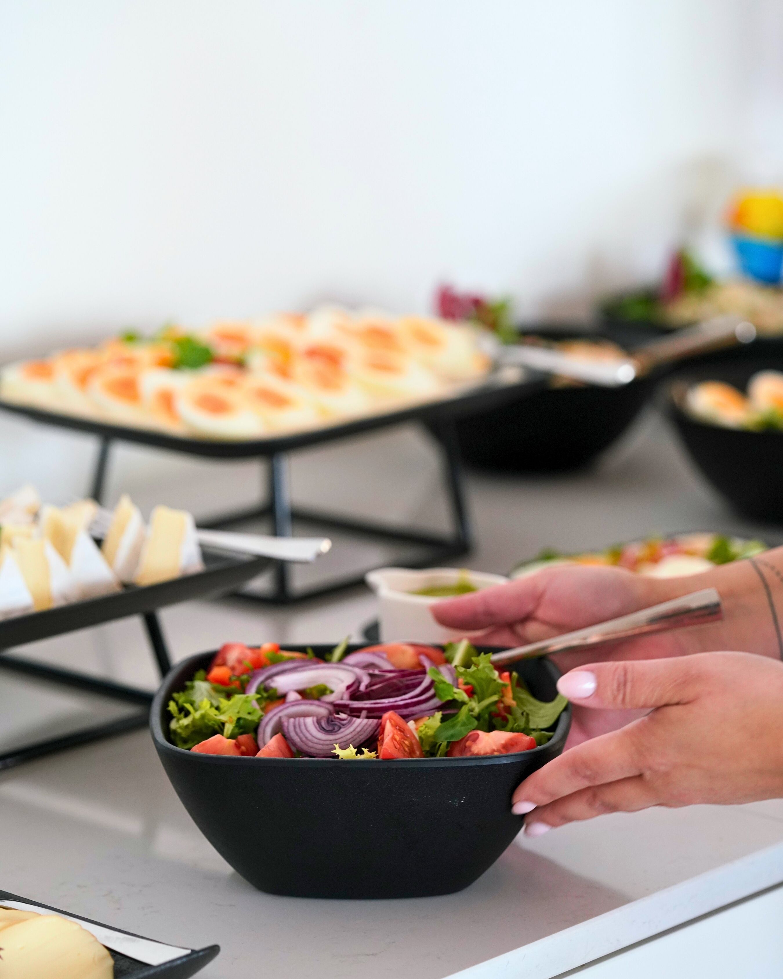 Una mesa de buffet con diversas opciones de comida, incluyendo un bol de ensalada y bandejas de aperitivos.