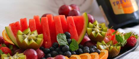 A fruit platter with various fruits and a bottle of champagne.