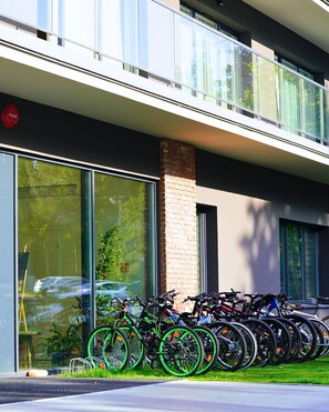 A modern building with a glass facade, a brick column, and a row of bicycles parked outside.