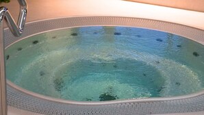 A hot tub with a metal faucet, a window with a view of a house, and a green wall.