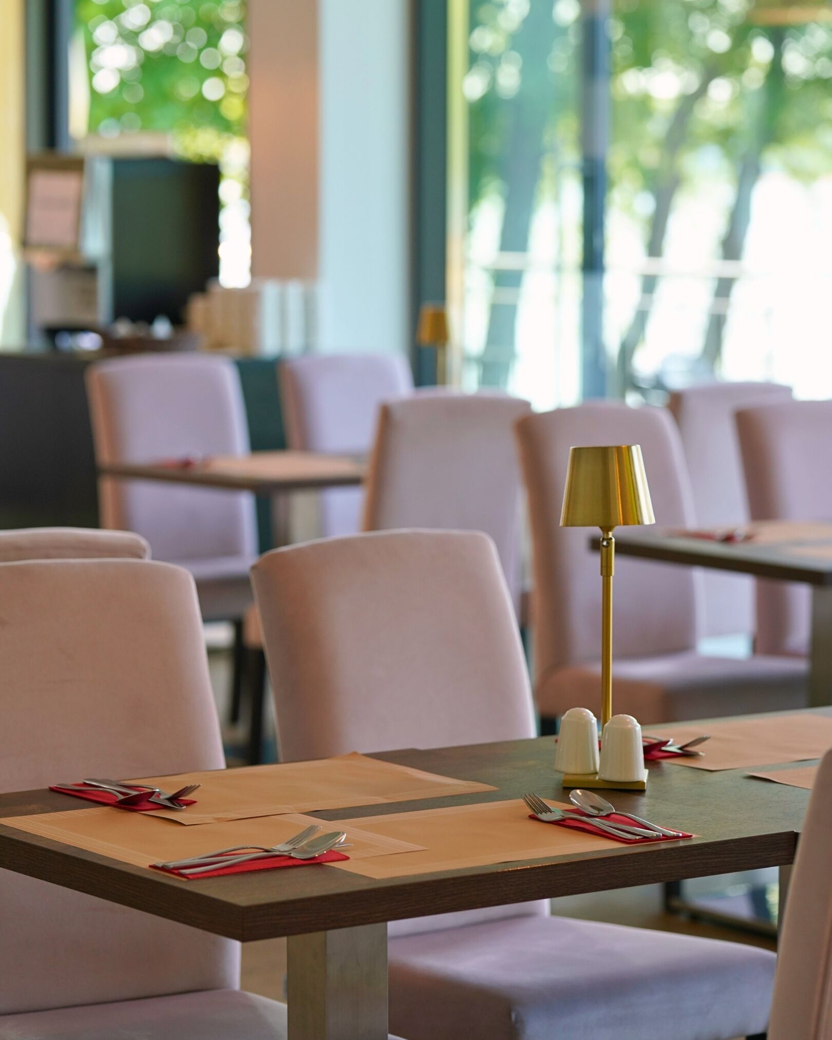 A dining area with tables set for two, each with cutlery and napkins.