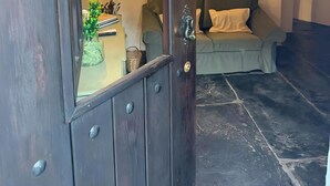 A dark wooden door with a small window, a lamp, a sofa, and a staircase in the background.